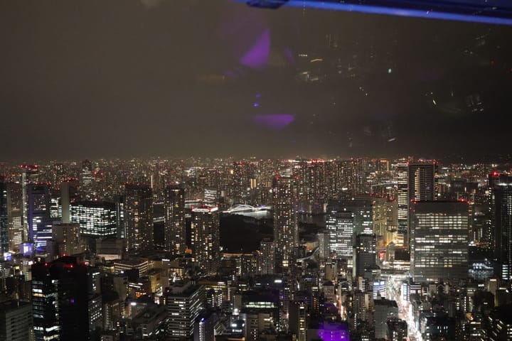 night sky view from tokyo tower, slightly hazy, low glow of lights across the sky, thumbnail