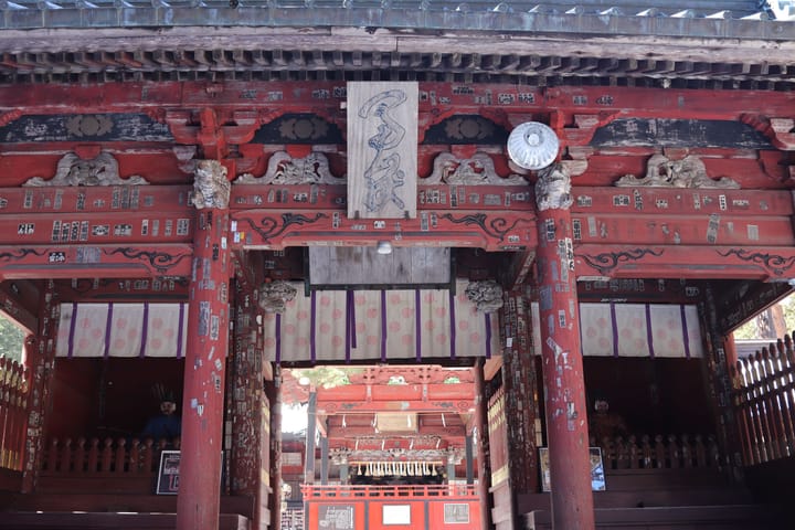 Red arching gate entrance, stickers covering the walls, thumbnail