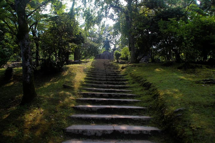 stone stairs built in to the side of a hill that go up to a statue at the top, thumbnail