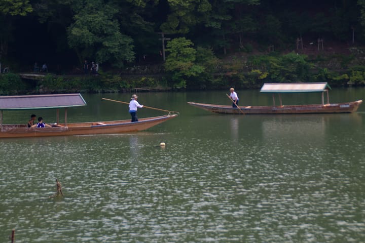 two boats passing each other being paddled by one person ferrying people across, thumbnail