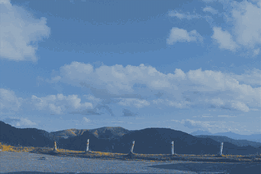 clouds in the blue sky, mountains below, posts in the ground